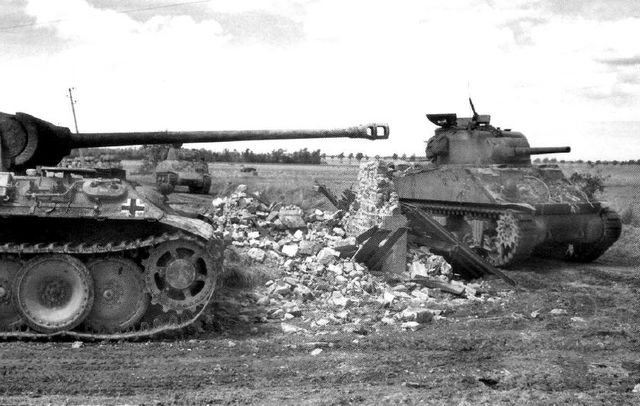 Rauray, Normandía, julio de 1944. Tanques Sherman de la 8º Armoured Brigade pasan junto a un Panzer V Panther puesto fuera de combate