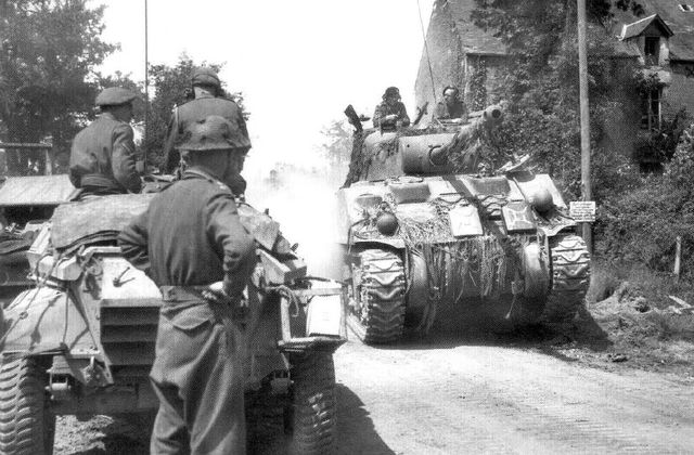Sherman Firefly pasa junto a un vehículo Humber en la población normanda de Aunay-sur-Odon. Agosto de 1944