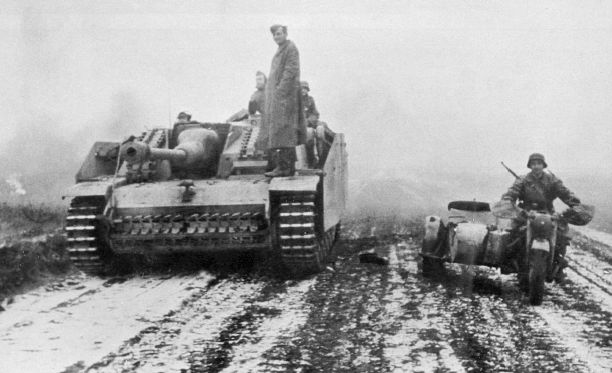 Un enlace motorizado pasa junto a un StuG III Ausf G en Ucrania durante el invierno de 1943-1944